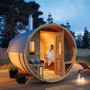 FinnTherm Fasssauna Sam: Runde Holzsauna mit Ofen und Frau im Bademantel. Ideal für entspannte Sauna-Momente im Garten.