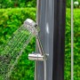Bestway Solarflow Gartendusche 35 l mit Handbrause und Wasserstrahl vor grünem Hintergrund.