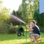 Mann und Kind bewässern Garten. Schwarzer Relaxdays Gartenschlauchwagen aus Metall/Kunststoff mit grüner Rolle.