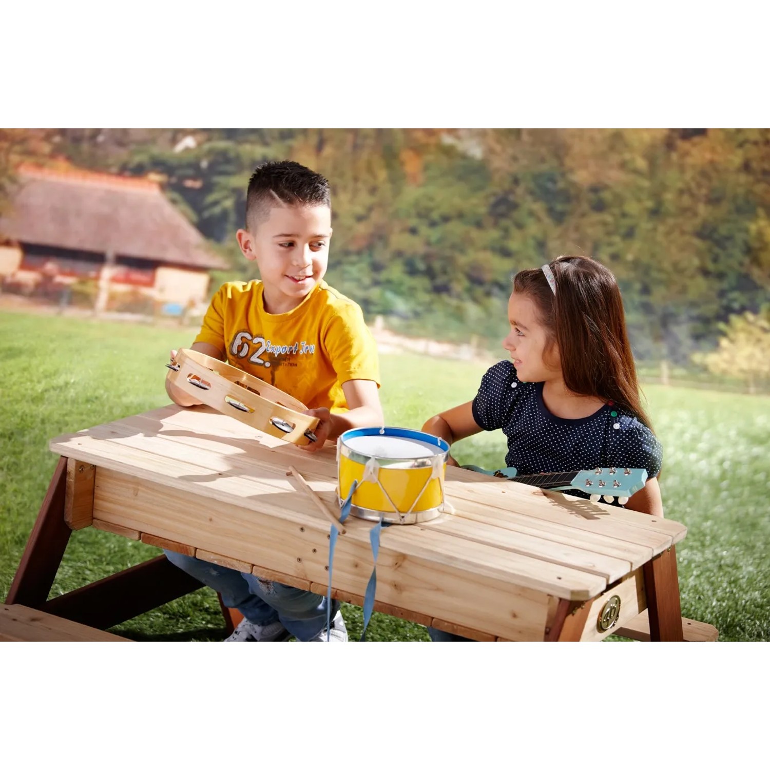 Kinder sitzen am Nick Sand- und Wasserspieltisch Braun mit Musikinstrumenten im Garten.