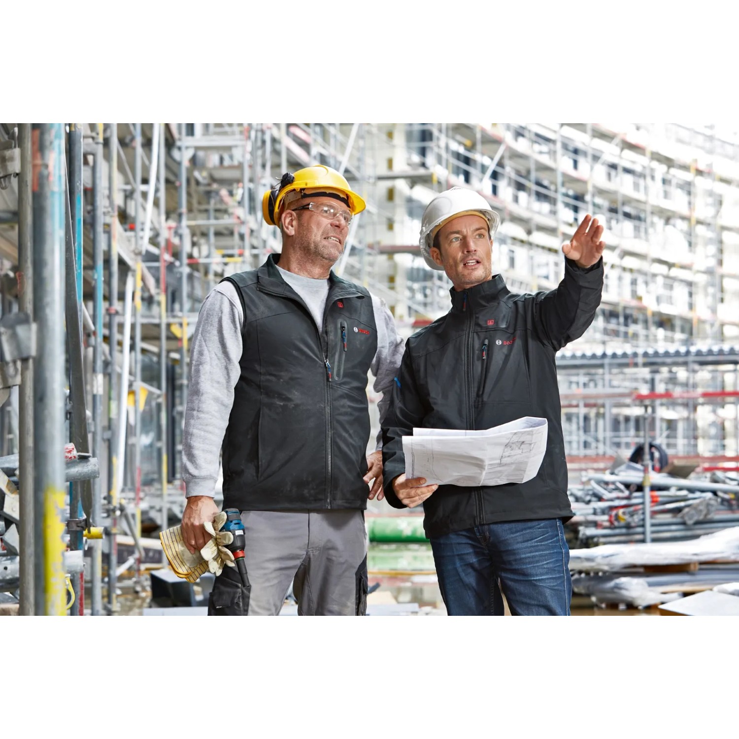 Bosch Professional Akku-Heizweste GHV 12+18V XA in Schwarz im Einsatz auf einer Baustelle.