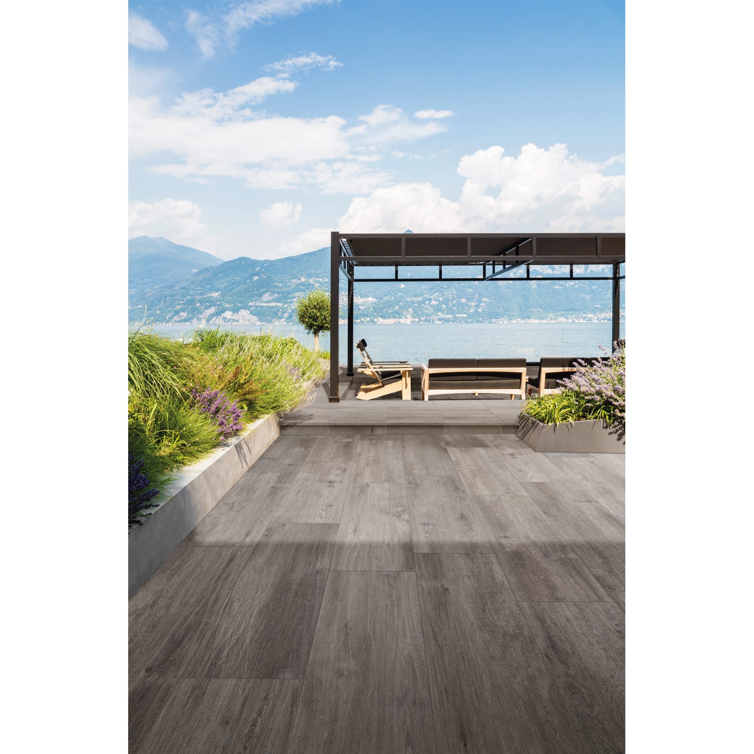 Eurostone Terrassenplatten TimberTwo Grigio, braungraues Feinsteinzeug in Holzoptik auf Terrasse am See.