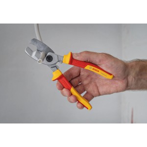 Bosch Professional VDE-Kabelschere (200 mm) schneidet Kabel. Zange mit rot-gelben Griffen in Hand.