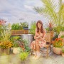 Frau liest auf Terrasse mit Gardena AquaBloom L Solar-Bewässerung für bis zu 30 Pflanzen.