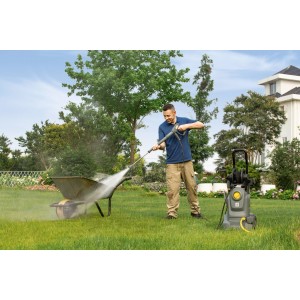 Mann reinigt Schubkarre mit Kärcher Hochdruckreiniger HD 5/11 EX Plus Classic im Garten.