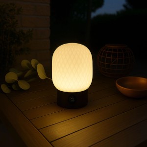 Brilliant Sarastro LED-Tischleuchte, 13cm, weißes Glas mit Diamantmuster, schwarzer Sockel, leuchtet warmweiß auf Holztisch.