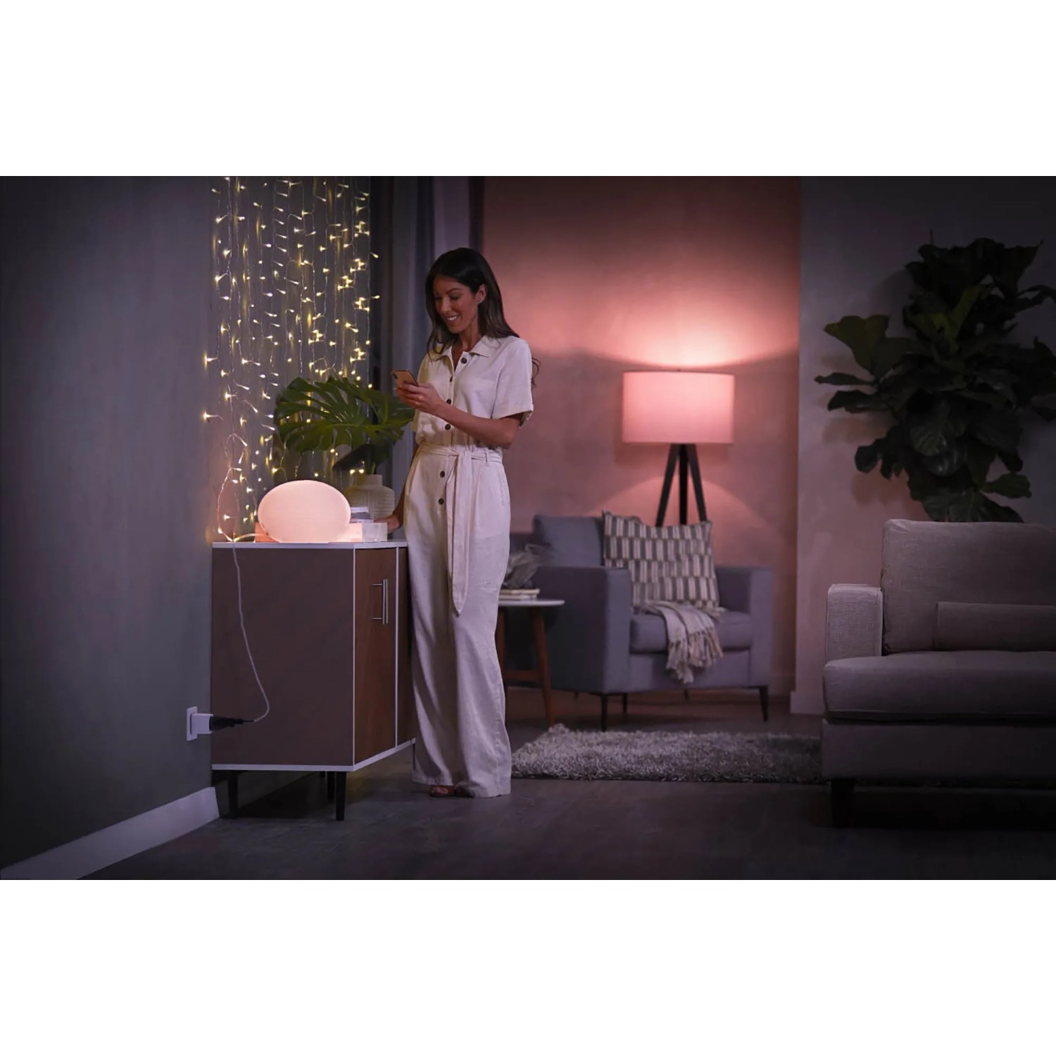 Philips Hue SmartPlug 4er-Pack in Anwendung: Frau steuert Lampe per App. Smarte Steuerung für dein Zuhause.