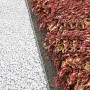 Bellissa Rasenkante aus verzinktem Metall trennt Kiesweg von Beet mit bunten Blättern.