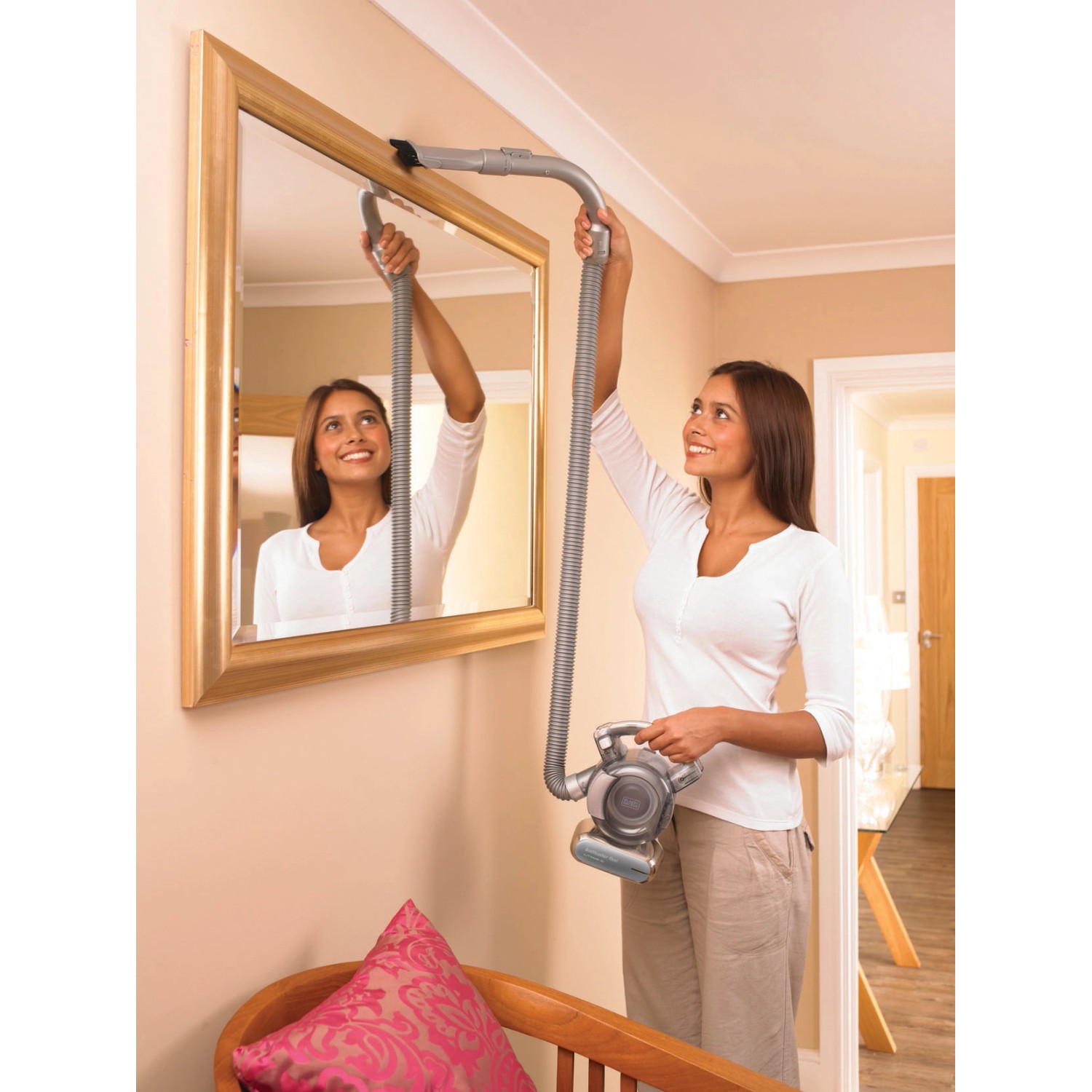 Frau reinigt Spiegel mit Black+Decker Akku-Handstaubsauger Dustbuster Flexi PD1820L.