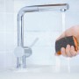 Hand hält LUX-TOOLS Schleifschwamm unter Wasserhahn. Schleifmittel für feine Oberflächen.
