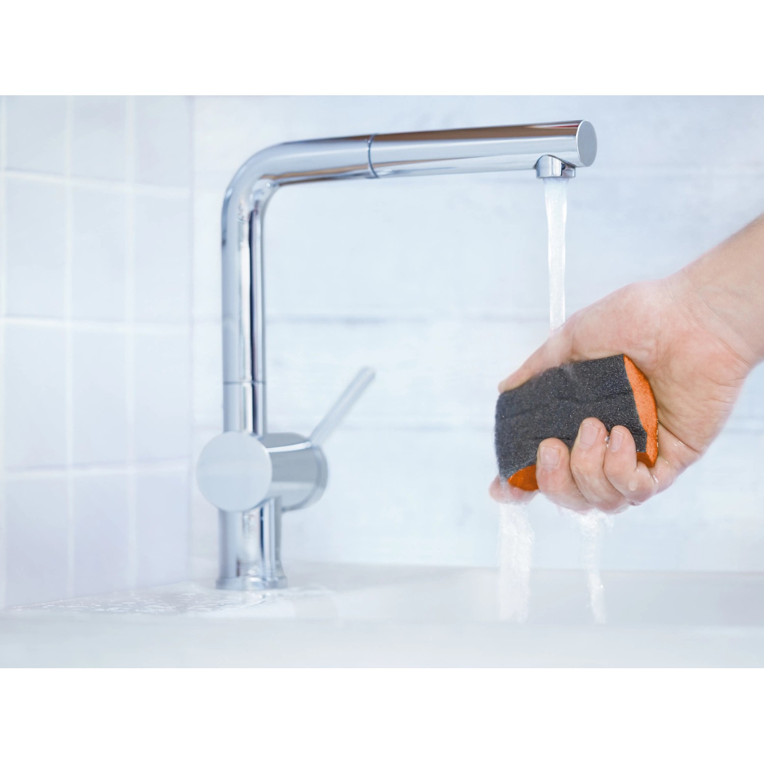 Hand hält LUX-TOOLS Schleifschwamm unter Wasserhahn. Schleifmittel für feine Oberflächen.
