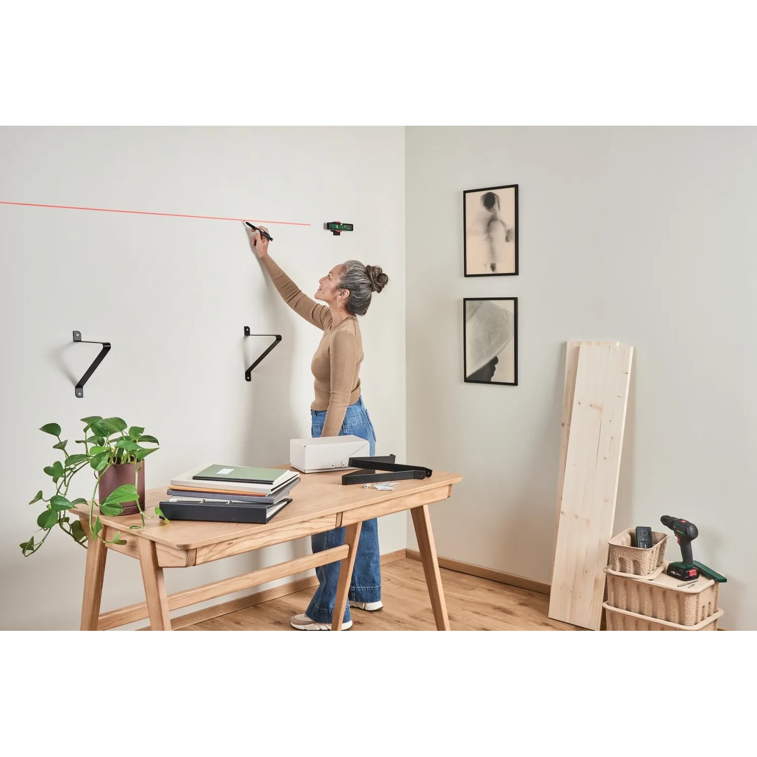 Frau markiert mit Bosch Laser-Wasserwaage UniversalWallLevel eine Linie an der Wand.