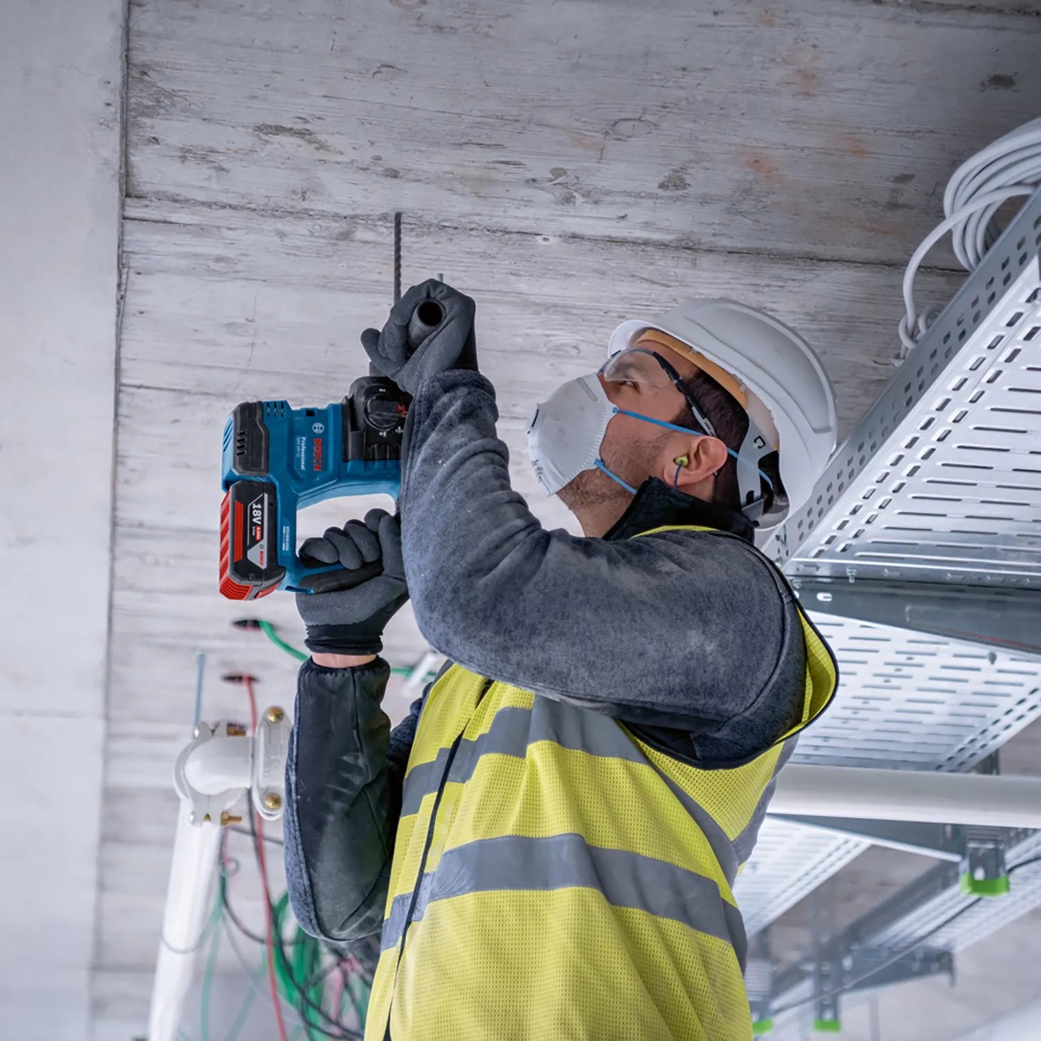 Handwerker bohrt mit Bosch Akku-Bohrhammer GBH 18V-22 aus dem Combi-Kit ein Loch in die Decke.