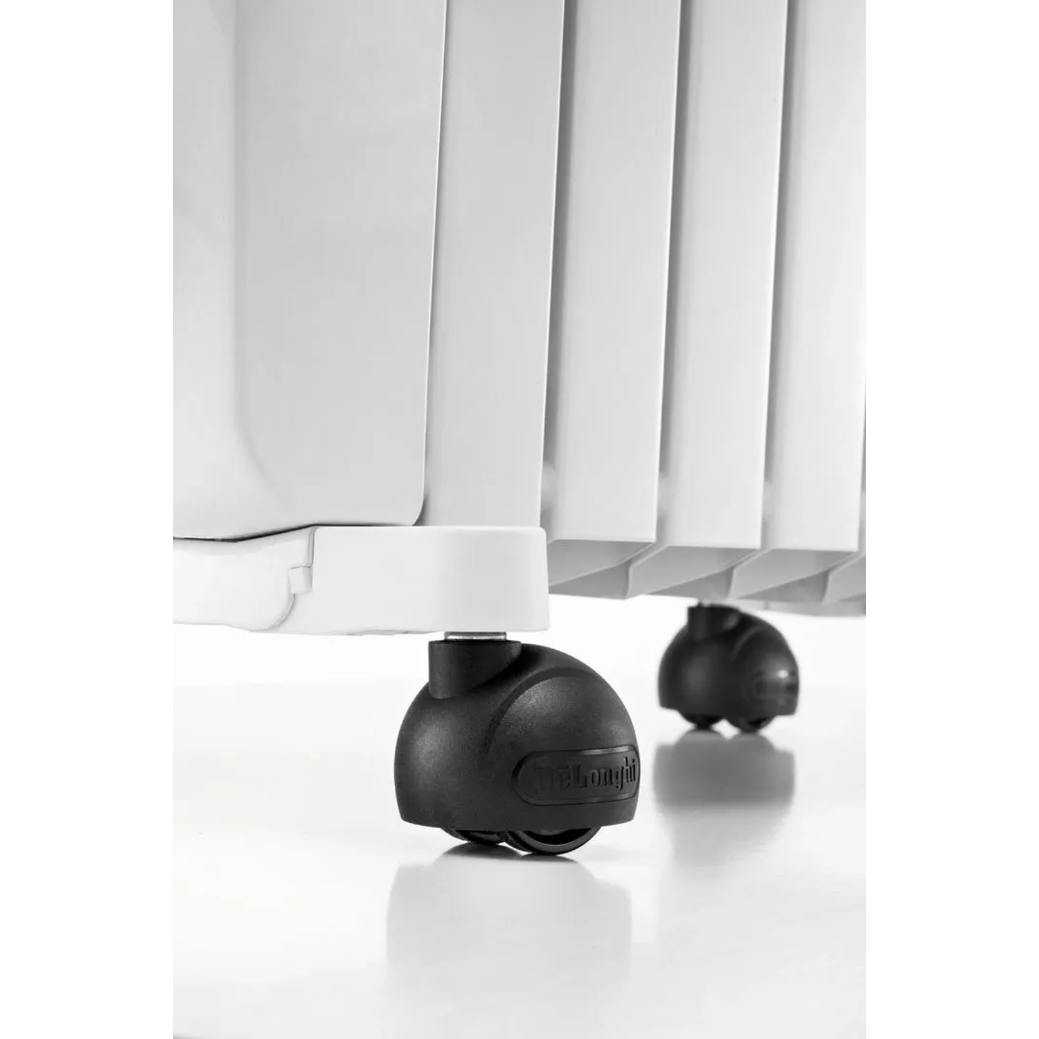 Detailaufnahme: Weißer De'Longhi Dragon 5 Radiator mit schwarzen Rollen. Elektrisches Heizgerät für Innenräume.