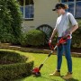 Frau trimmt Rasenkante mit Einhell Akku-Rasentrimmer GE-CT 18/28 Li-Solo im Garten.