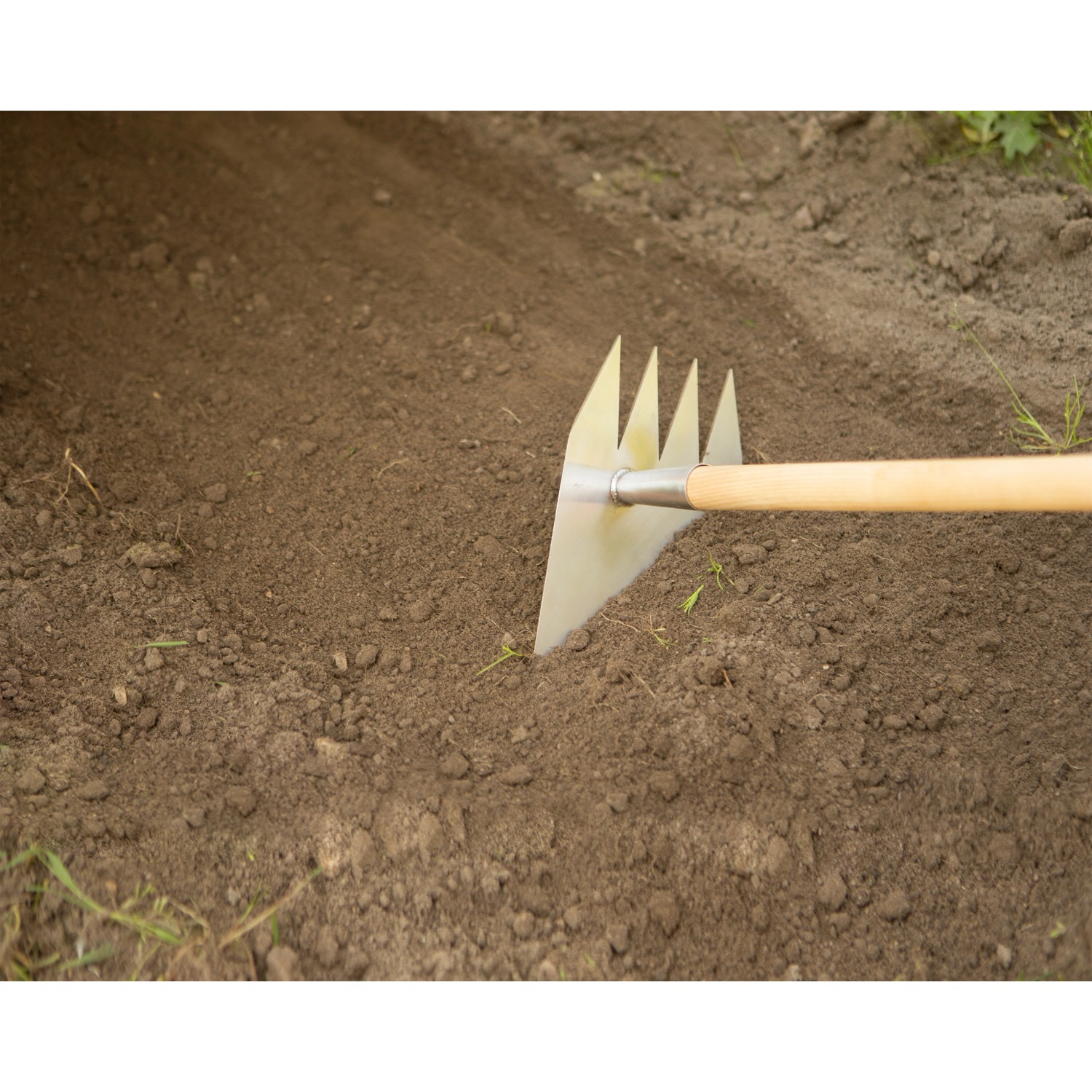 Ruwi Multi-Harke 8in1 aus Edelstahl bei der Bodenbearbeitung im Garten.