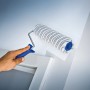 LUX Dispersionswalze 18 cm beim Streichen einer Wand, Farbwalze mit grau-gestreiftem Kurzflor.