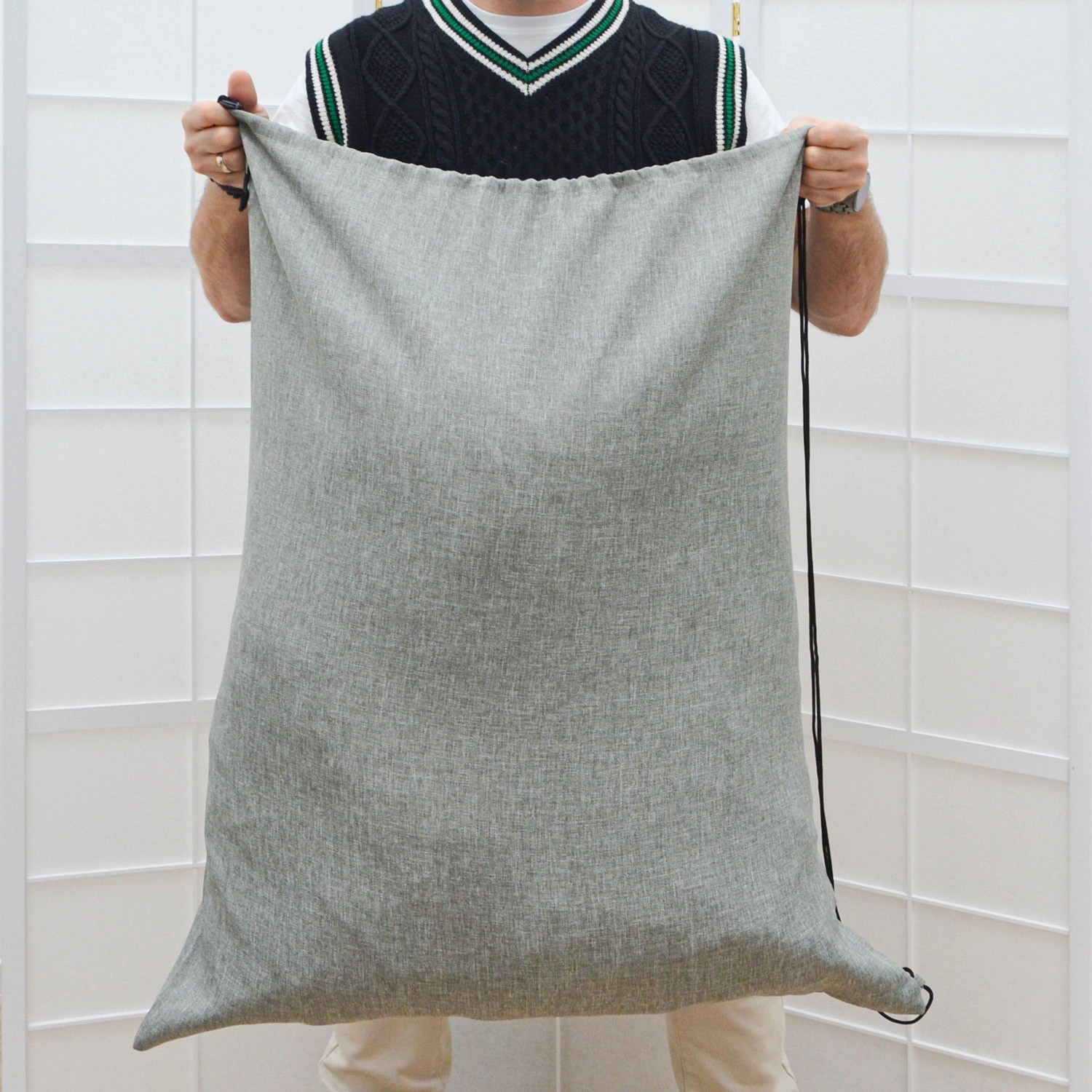 Grauer DuneDesign Wäschesack (100 & 60 Liter) mit Kordelzug, gehalten von einer Person.