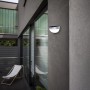 Lutec Solar-Wandleuchte Bubble aus Edelstahl an grauer Hauswand. Moderne Solarleuchte für den Außenbereich.