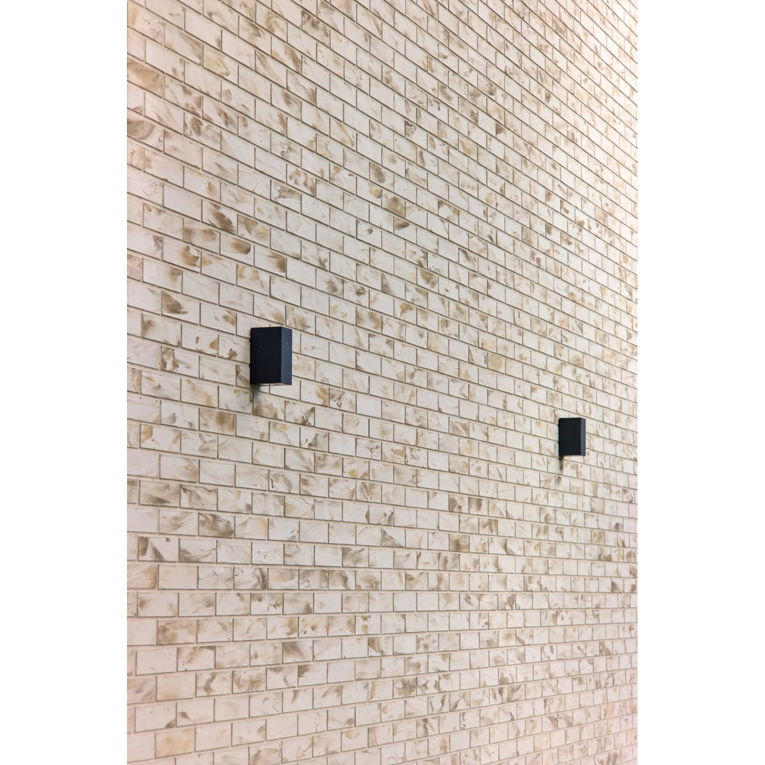 Wand mit Elabrick Eckverblender Sevilla in Beige und Braun, mit zwei schwarzen Wandleuchten.