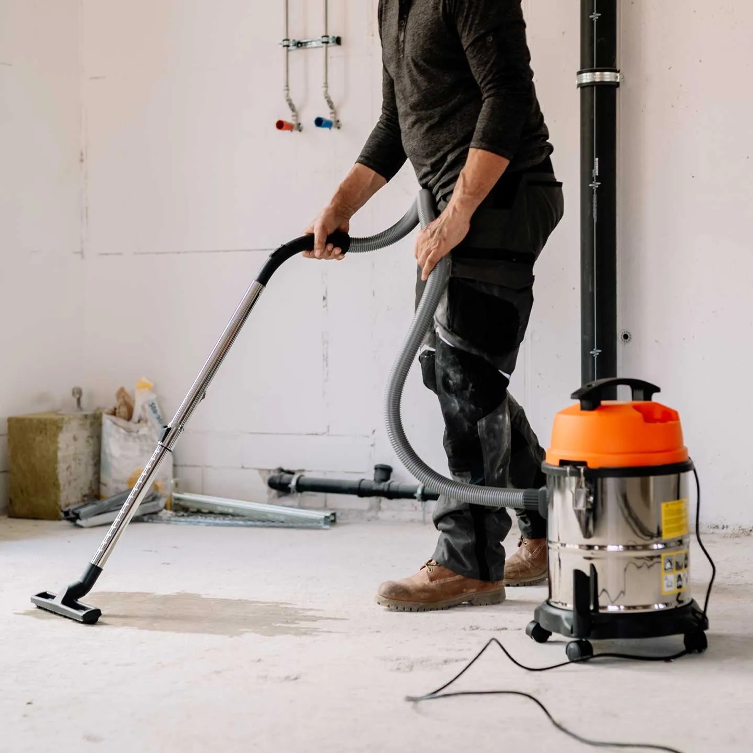 Mann saugt mit Cross Tools Nass-Trockensauger NTAS 1200 Werkstattboden.