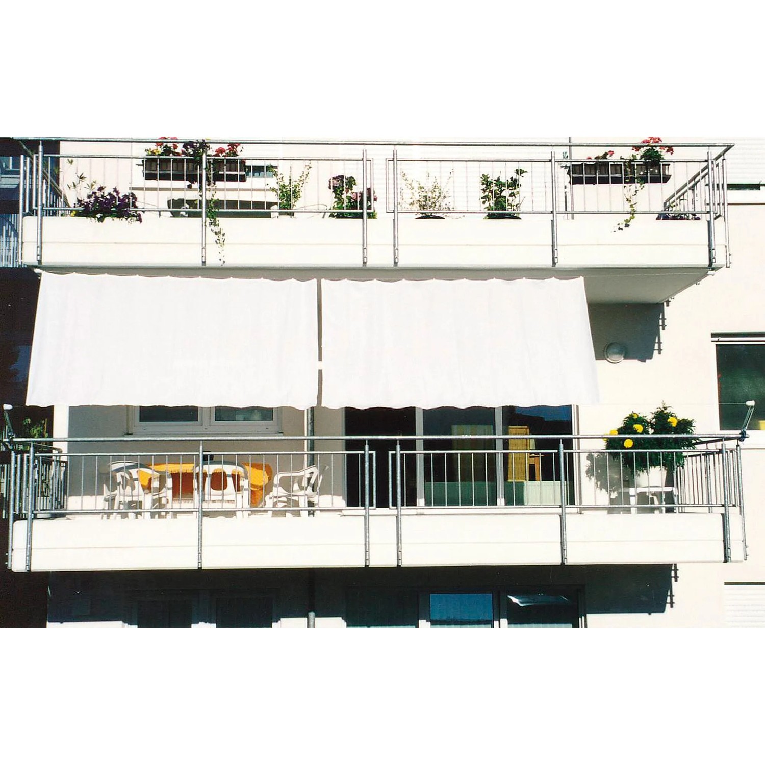 Weißer Floracord Balkonsichtschutz Bausatz II (270x140cm) an einem Balkon mit Tisch und Stühlen.