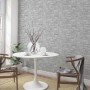 Graue Marburg Vliestapete GZSZ in 3D Steinoptik im Wohnraum mit Tisch und Stühlen.