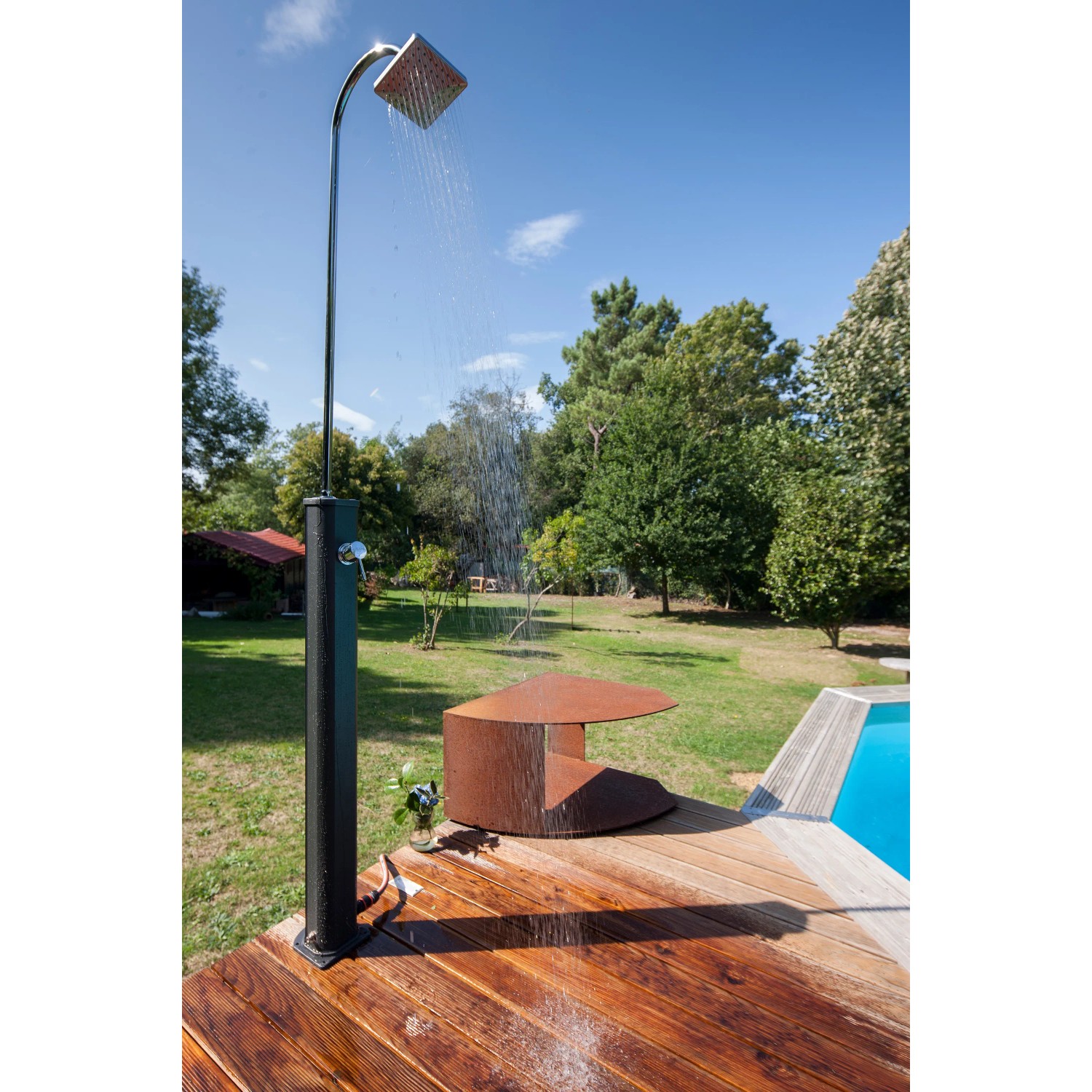 Schwarze Gre Solardusche aus Aluminium (18 l) im Garten mit Wasserstrahl.