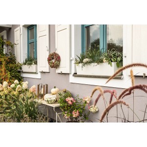 Weißer Lechuza Balconera Color 80 Blumenkasten mit Bepflanzung vor einem Fenster.