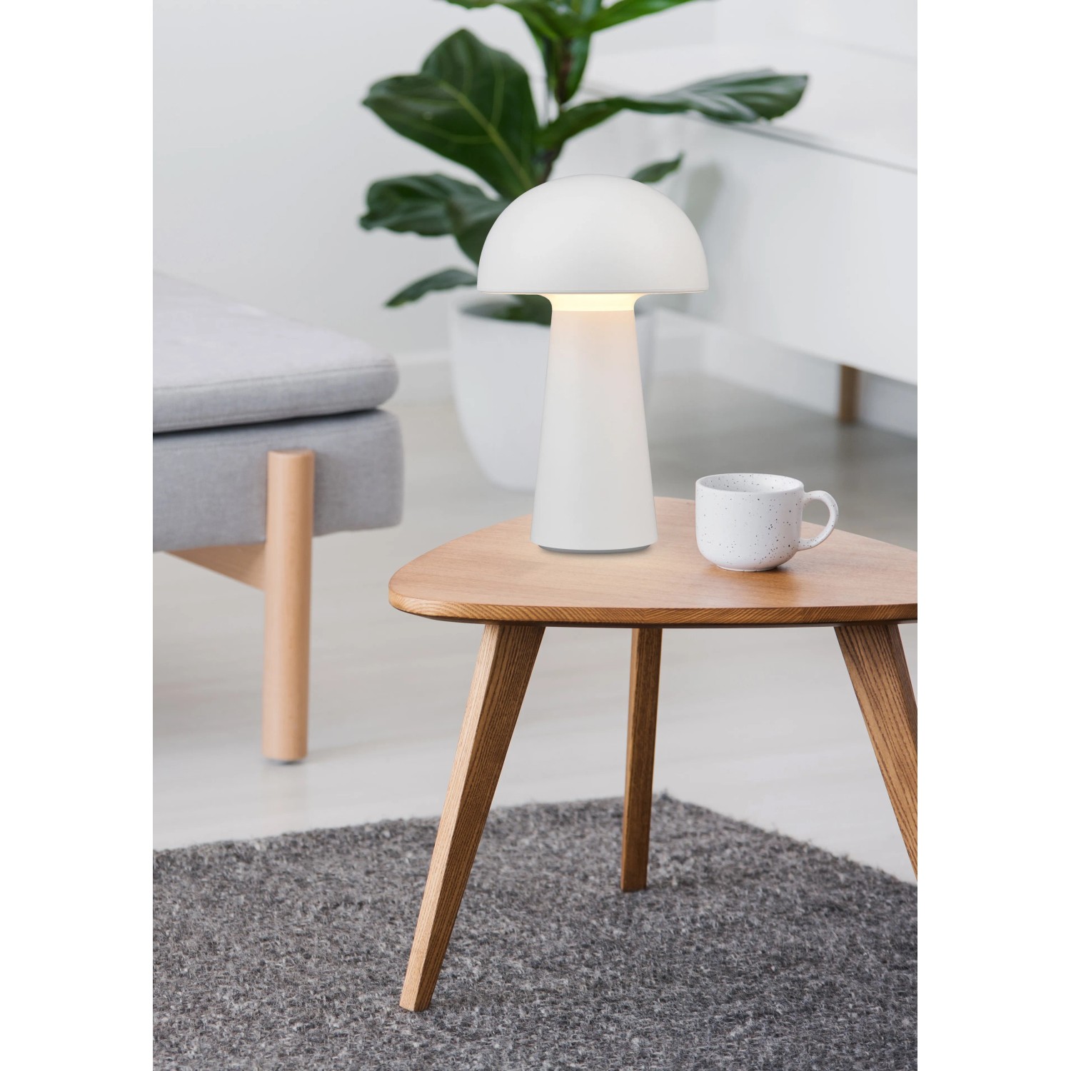 Weiße Reality LED-Tischleuchte Lennon im Pilzdesign auf einem Tisch. Dekorative Lampe für Innen und Außen.