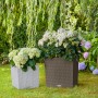 Lechuza Cube Cottage Pflanzgefäße, 30x30x30 cm, lichtgrau und braun, mit Pflanzen im Garten.