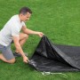 Bestway Pool Abdeckplane, schwarz, Ø 305 cm, PVC, Mann kniet daneben.