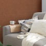 Rot strukturierte Vliestapete Uni Matt an Wand hinter Sofa mit Kissen und Decke.