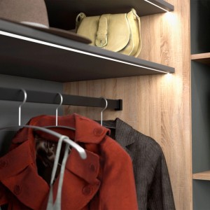 Schwarz matt lackierte SOTECH Schrankstangenlager halten eine rechteckige Garderobenstange mit Kleidung in einem modernen Kleiderschrank.