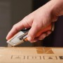 Hand schneidet Karton mit Fiskars Universalmesser CarbonMax™.