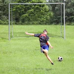 SPORTNOW Fußballtor aus grauem Stahl mit schwarzem Netz auf Rasen. Ein Spieler schießt auf das Tor.
