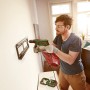 Mann bohrt mit Bosch EasyImpact 600 Schlagbohrmaschine in Wand. Inkl. Tiefenanschlag.