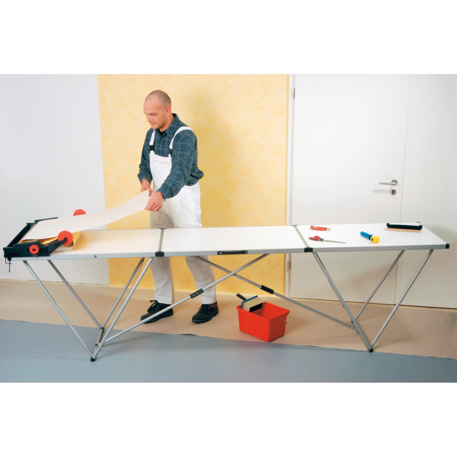 LUX Multifunktionstisch mit Alu-Gestell beim Tapezieren. Tapeziertisch mit Werkzeug und Person.