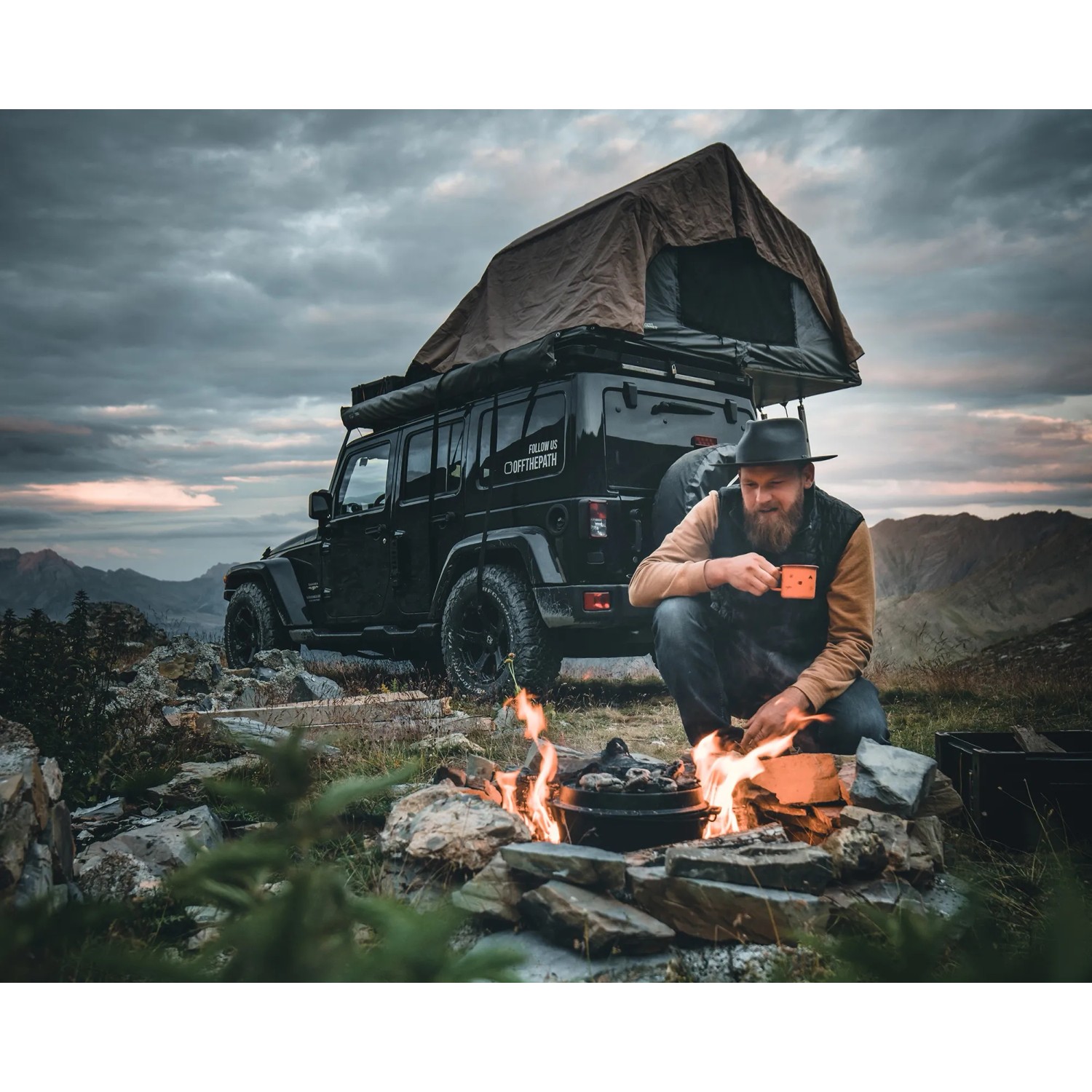 Petromax Dutch Oven Set am Lagerfeuer mit Outdoor-Abenteurer und Geländewagen mit Dachzelt.