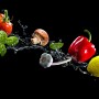 Glasbild Flying Vegetables, 80x30 cm, mit Gemüse und Wasser auf schwarzem Hintergrund.