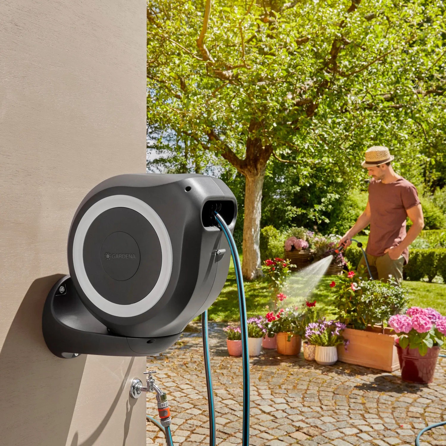 Gardena Wand-Schlauchbox RollUp M mit 20m Schlauch im Einsatz beim Bewässern von Blumen.