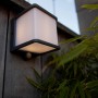 Anthrazitfarbene Lutec LED Solar Wandleuchte Doblo mit Bewegungsmelder an Holzwand.