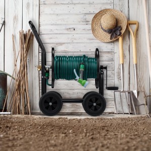 Schwarzer Metall-Schlauchwagen mit grünem Gartenschlauch, Sprühdüse und vier Rädern vor Holzwand im Garten.