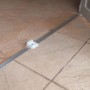 Detailaufnahme einer Bodenschiene für ein Grosfillex Gartenhaus, montiert auf Fliesen.