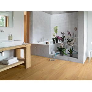 Muster Vinyl Basic 5.3 Eiche Natur gebürstet im Badezimmer mit Holztisch und Badewanne.