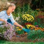 Frau arbeitet im Garten mit Gardena combisystem-Kleingeräte-Verlängerungsstiel 78 cm und Rechen.