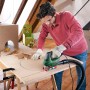 Mann sägt Kreis mit Bosch Stichsäge PST 900 PEL in Holzplatte. Staubabsaugung angeschlossen.