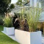 Weiße Vivanno Pflanzkübel Maxi (100x45x45 cm) mit Bepflanzung im Garten.