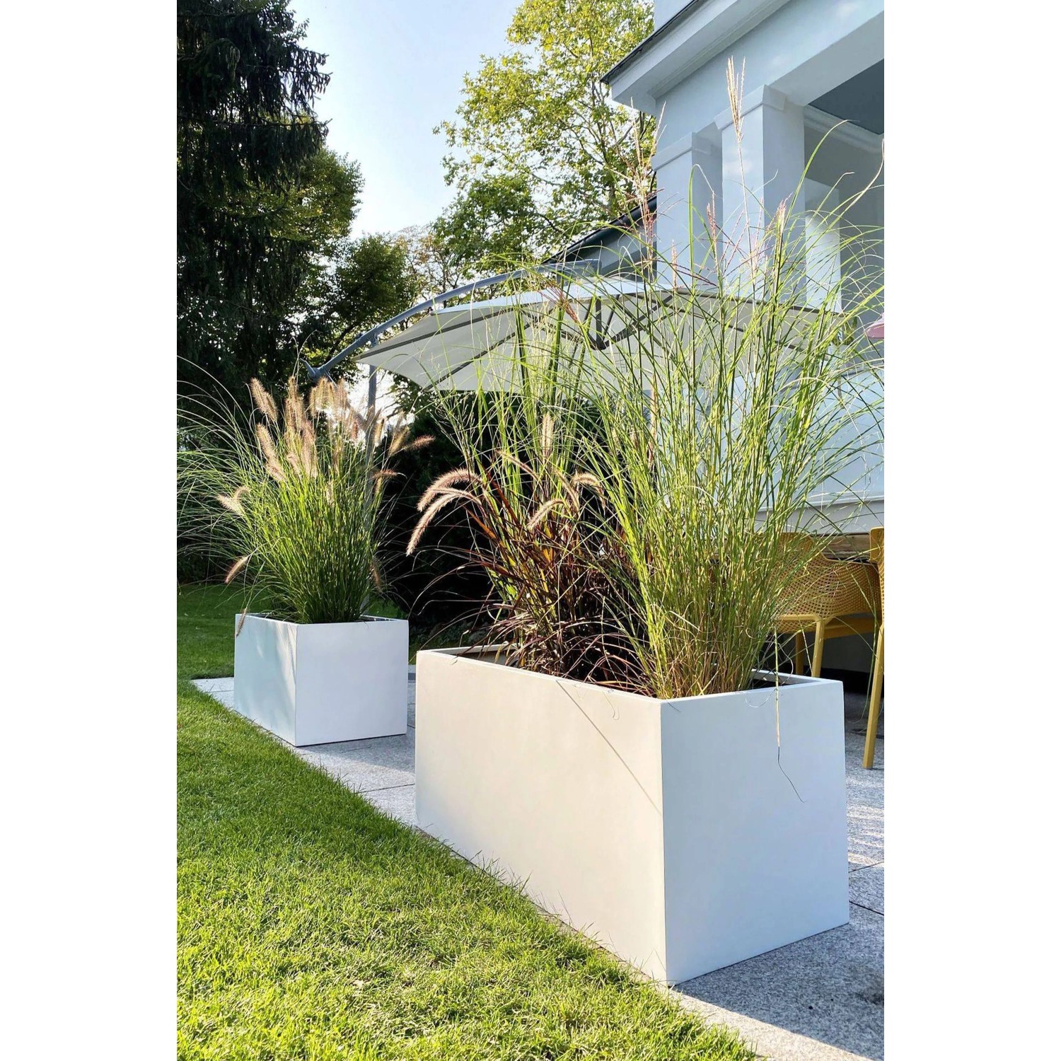 Weiße Vivanno Pflanzkübel Maxi (100x45x45 cm) mit Bepflanzung im Garten.