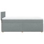Helles Boxspringbett 90x200 cm mit Matratze und Kopfteil, grauer Stoffbezug.